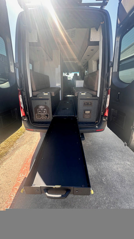 RV rental interior showcasing a large pull-out storage drawer, custom benches, and power station, perfect for mobile adventures.