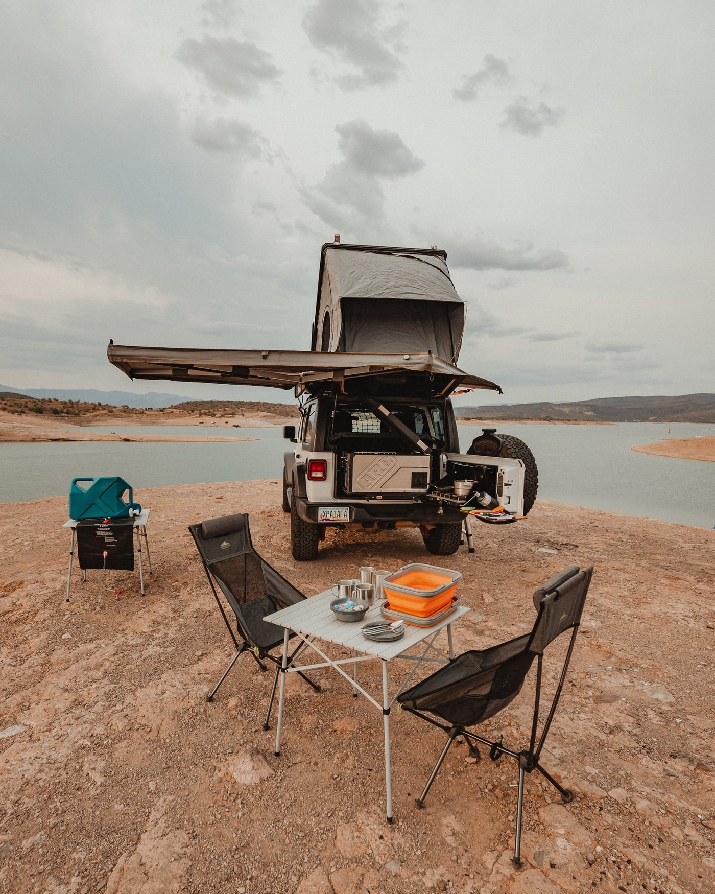 Explore by lake with this overlanding Jeep rv rental, featuring a rooftop tent, awning, and full camp kitchen setup. — photo 19