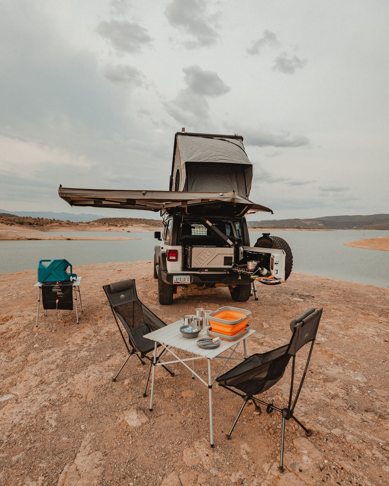 Explore by lake with this overlanding Jeep rv rental, featuring a rooftop tent, awning, and full camp kitchen setup. — photo 19