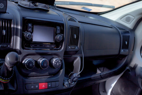 RV rental dashboard showcasing the infotainment screen, climate control dials, gear stick, and USB charging.