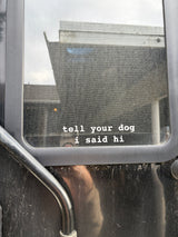 A dusty RV rental window with a screen displays 'tell your dog i said hi', hinting at dog-friendly travel.