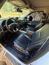 View inside a Ford F-Series truck, ideal for an RV rental. Features black leather seats, dashboard, and steering wheel.