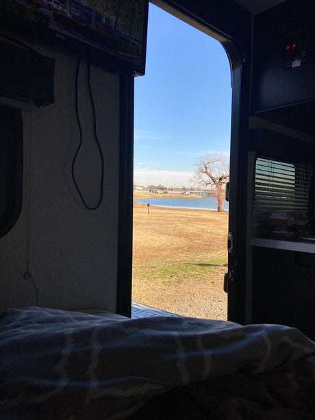 Enjoying the lake view from an RV rental. Cozy travel setup with an open door to nature. Ideal for serene camping.