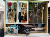 An RV rental kitchen drawer, showcasing well-organized cutlery, cooking tools, and can koozies for compact living.