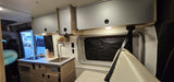 This RV rental's interior features a bright kitchen with sink, stove, and overhead cabinets, plus comfortable seating.