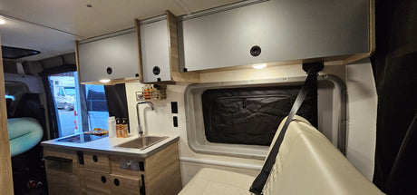 This RV rental's interior features a bright kitchen with sink, stove, and overhead cabinets, plus comfortable seating.