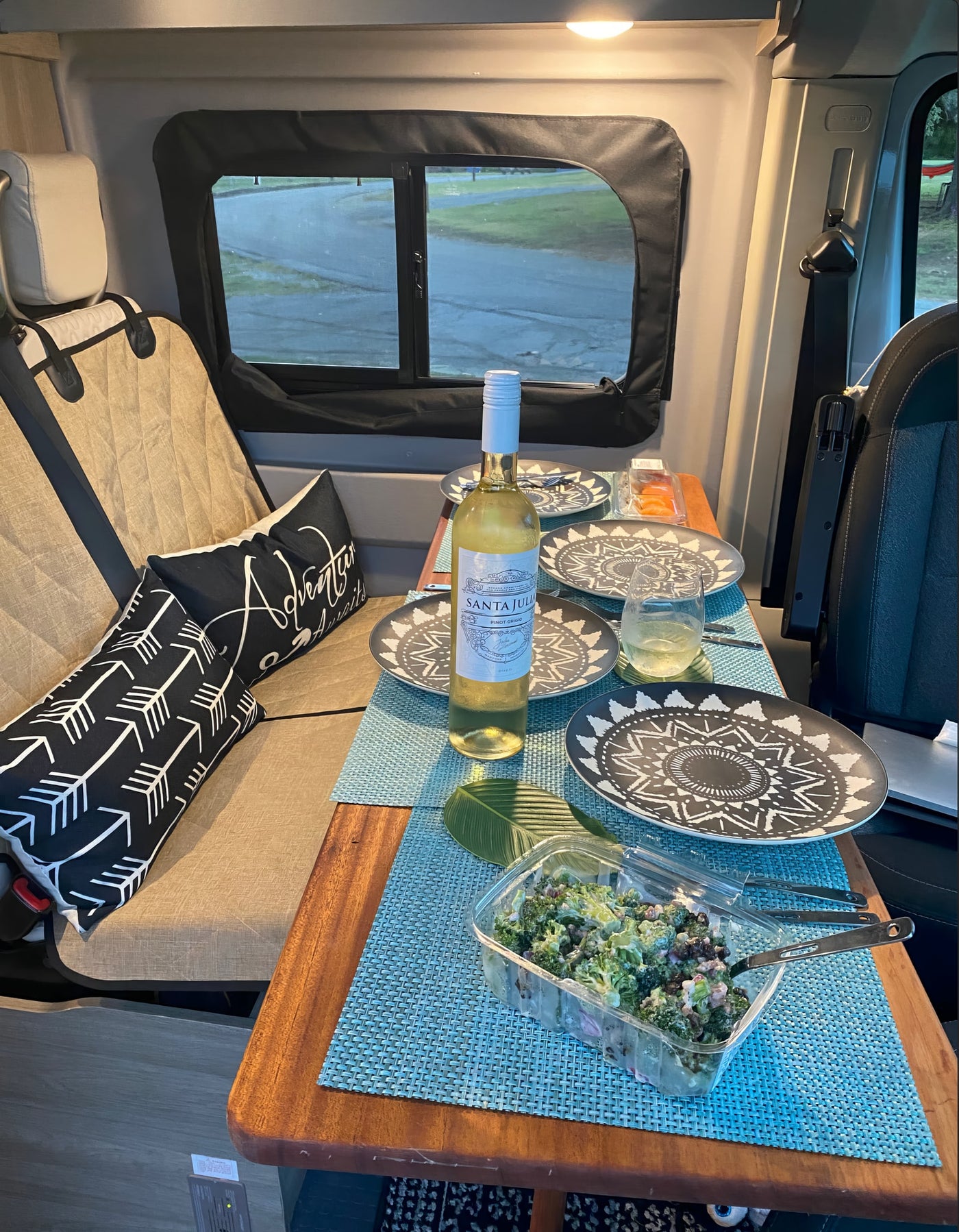 Cozy RV rental interior with wine, salad, and dinnerware set for a relaxing meal. — photo 9