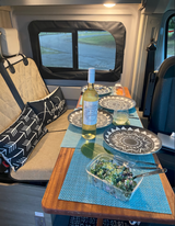 Cozy RV rental interior with wine, salad, and dinnerware set for a relaxing meal.