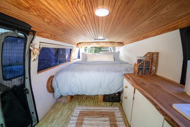 Cozy rv rental interior with a light blue bed, wooden ceiling, and ample storage, perfect for a comfortable road trip.
