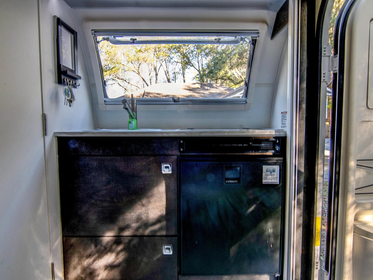  and large windows revealing green foliage outside.|Cozy rv rental living area featuring an L-shaped sofa — photo 19