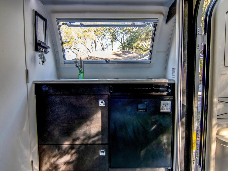  and large windows revealing green foliage outside.|Cozy rv rental living area featuring an L-shaped sofa — photo 19
