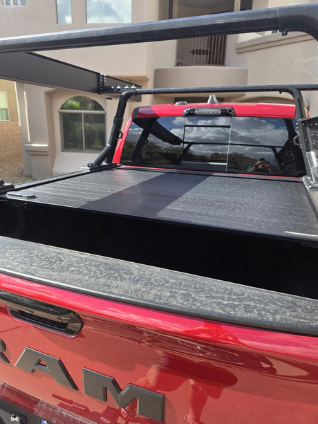 Close view of the Retrax Pro XR cover slats across the RAM 1500 bed with the Yakima OverHaul HD rack uprights and crossbars above