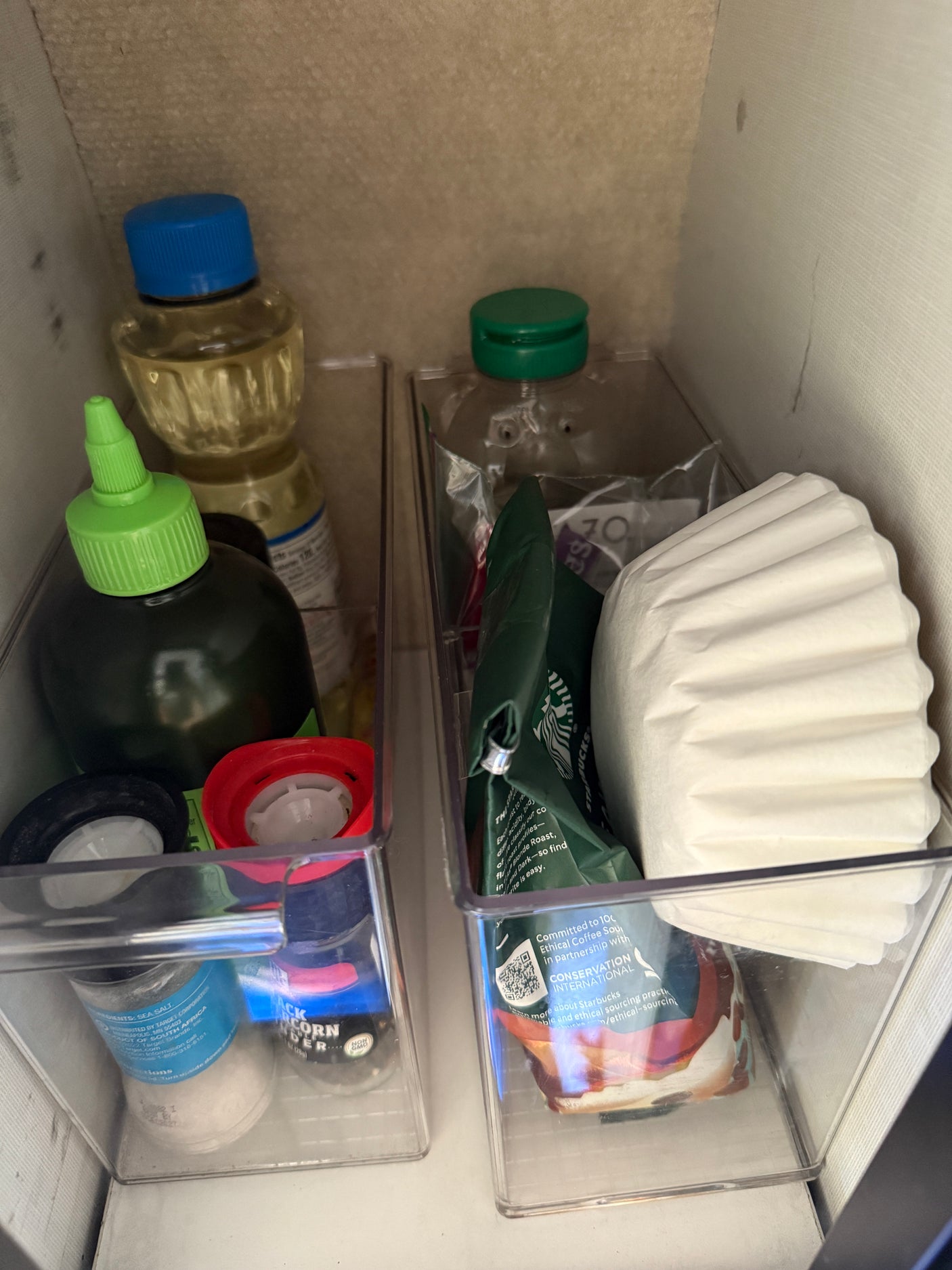 Organized pantry staples in clear bins, ideal for compact RV rental kitchen storage: coffee, spices, and oils.