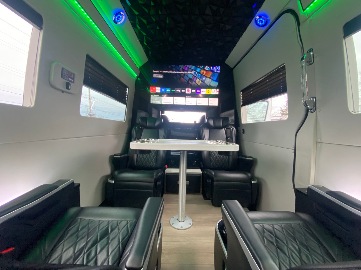 This RV rental features a luxury interior with four leather seats, a central table, and a large smart TV for entertainment. — photo 3