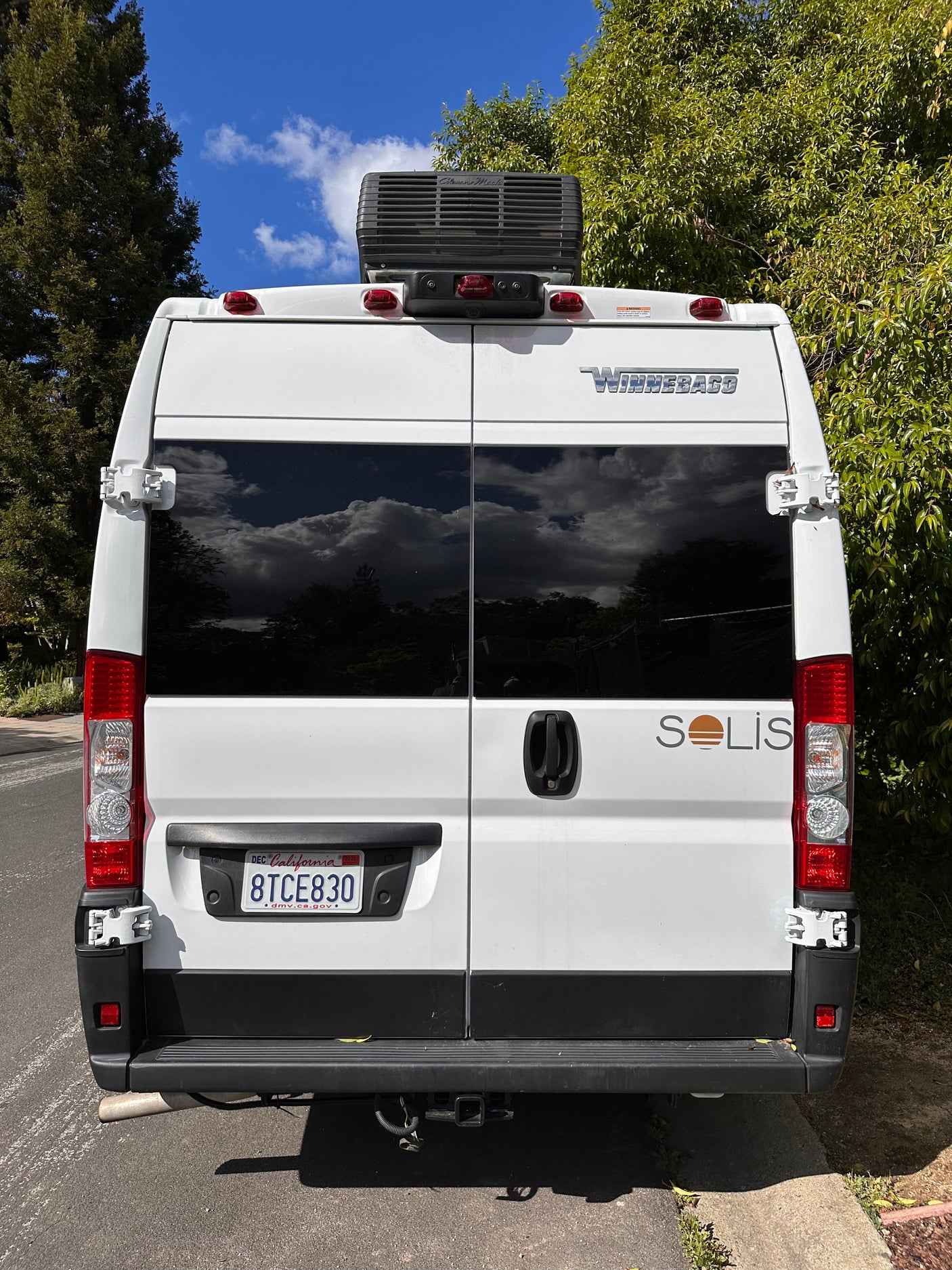 Rear of a white Winnebago Solis camper van, an ideal rv rental for California adventures. Note the rooftop AC unit.
