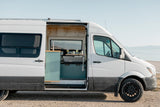 White Sprinter RV rental by a lake, showcasing its cozy, customized interior for adventure travel and van life.