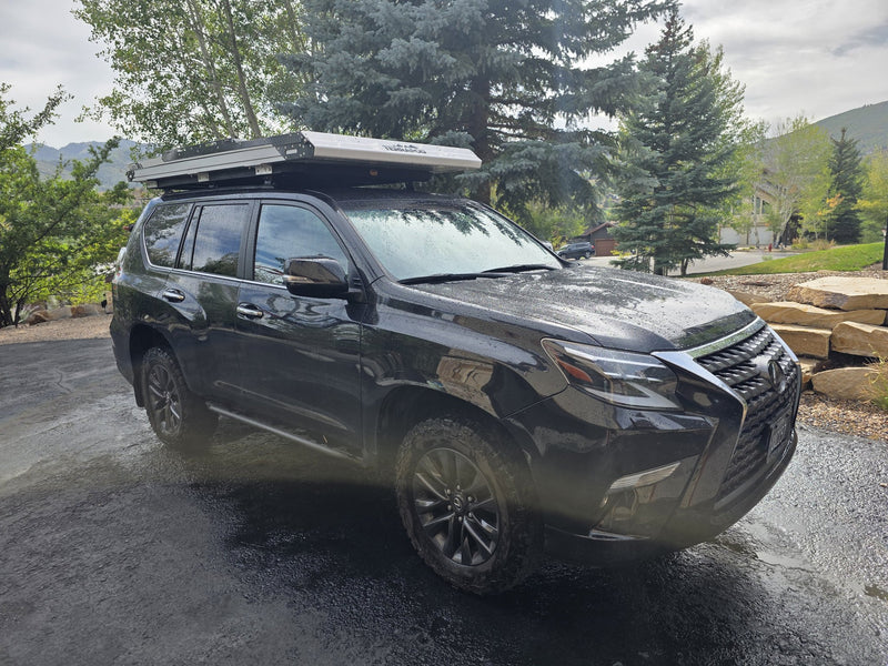 Passenger-side full view of the closed Terrapod RTTx XL rooftop tent mounted on a black Lexus GX460 parked in a driveway, showing the packed tent's height relative to the roofline — photo 8