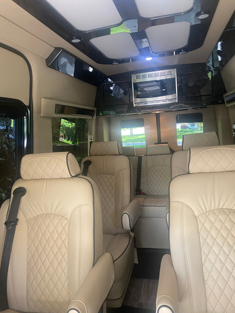 RV rental's luxurious interior: cream quilted leather seats, microwave, and elegant overhead lighting.