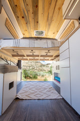 Experience comfort in this rv rental. A cozy bed, wood ceiling, and ample storage lead to scenic mountain views.