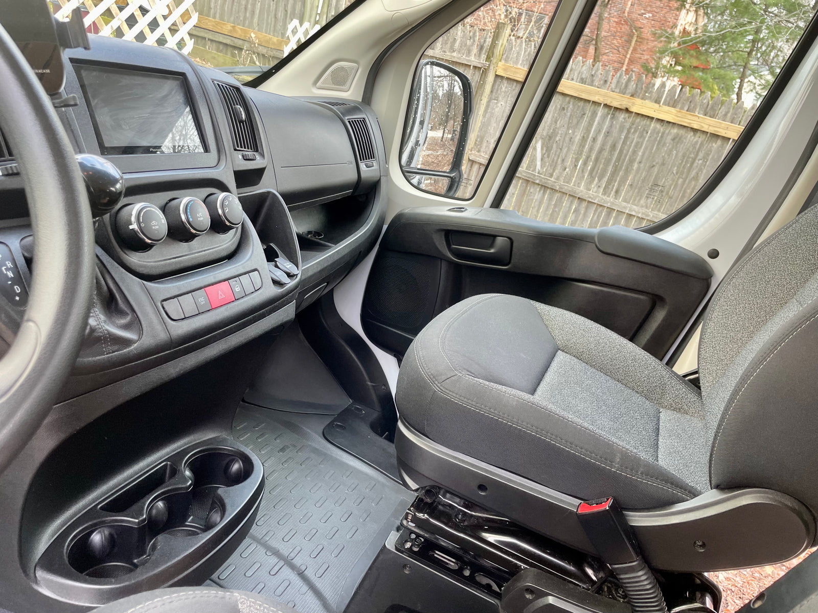 RV rental van's passenger interior: dashboard with Pioneer screen, climate controls, cupholders, and fabric seat.