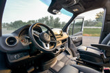 Step inside this rv rental! Driver's cockpit of a modern Mercedes-Benz Sprinter van, dashboard & open door view.