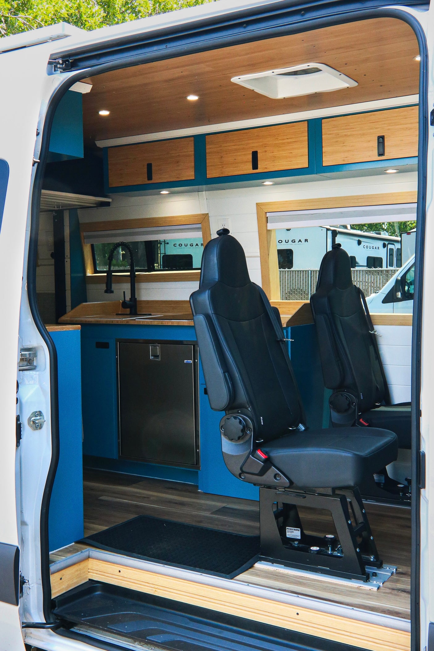 Explore this custom rv rental interior! Featuring a compact kitchen, adjustable passenger seating, and a modern design.