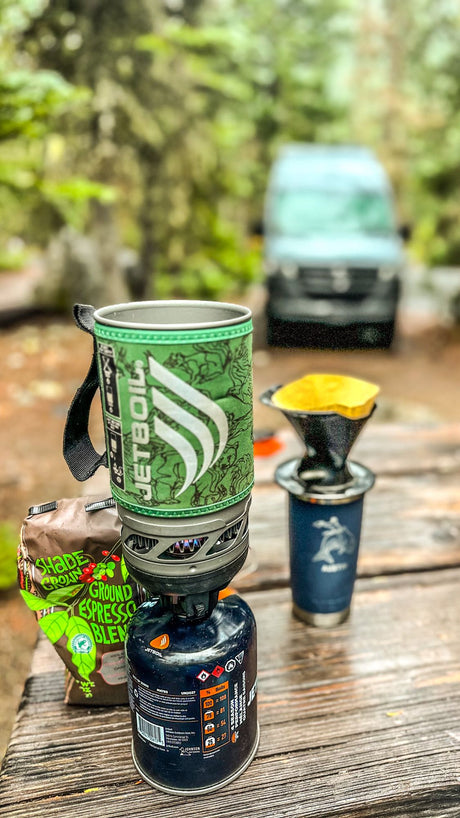 Brewing morning coffee with a JetBoil and ground espresso on a wooden table. The perfect start to an RV rental adventure.