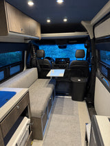 RV rental: Campervan interior showing a compact living space with bench seating, kitchen area, and front cabin view.