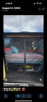 Cozy camper van setup: bed, pillows, and gear storage seen through a mesh screen. Perfect for an rv rental adventure!
