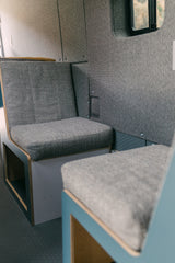 Modern grey upholstered seating and paneling in a clean RV rental interior, ready for comfortable camper van travel.
