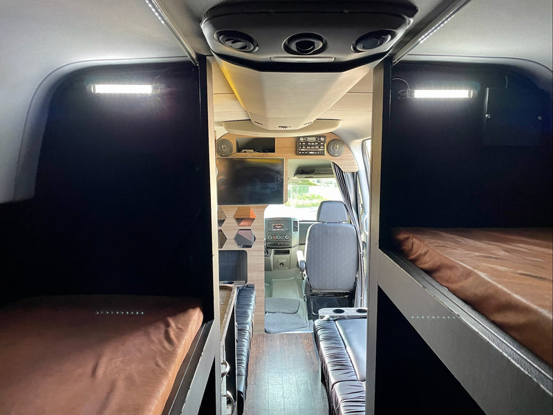 Spacious RV rental interior featuring a central aisle leading to the cockpit, with dark bunk beds on both sides. — photo 12