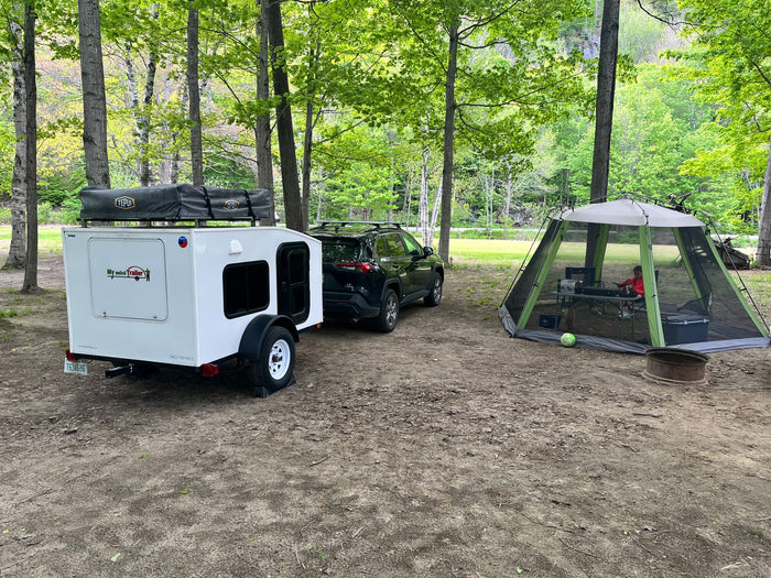  next to a red pickup truck.|Experience nature with this white compact travel trailer. Perfect for an RV rental