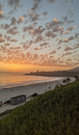 Vibrant sunset over a tranquil beach, coastal bluffs, and patterned clouds. A perfect backdrop for your next rv rental adventure.