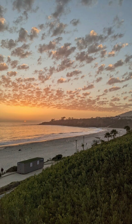 Vibrant sunset over a tranquil beach, coastal bluffs, and patterned clouds. A perfect backdrop for your next rv rental adventure.