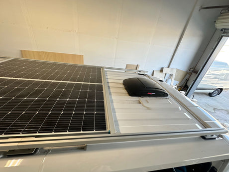 Upgraded RV rental rooftop: dual solar panels & MaxxFan for sustainable, off-grid campervan living.