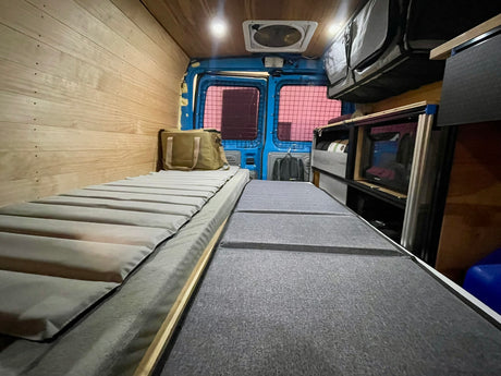 RV rental camper van interior: Two beds, wood walls, overhead storage, and rear cargo doors. Ready for your next adventure!