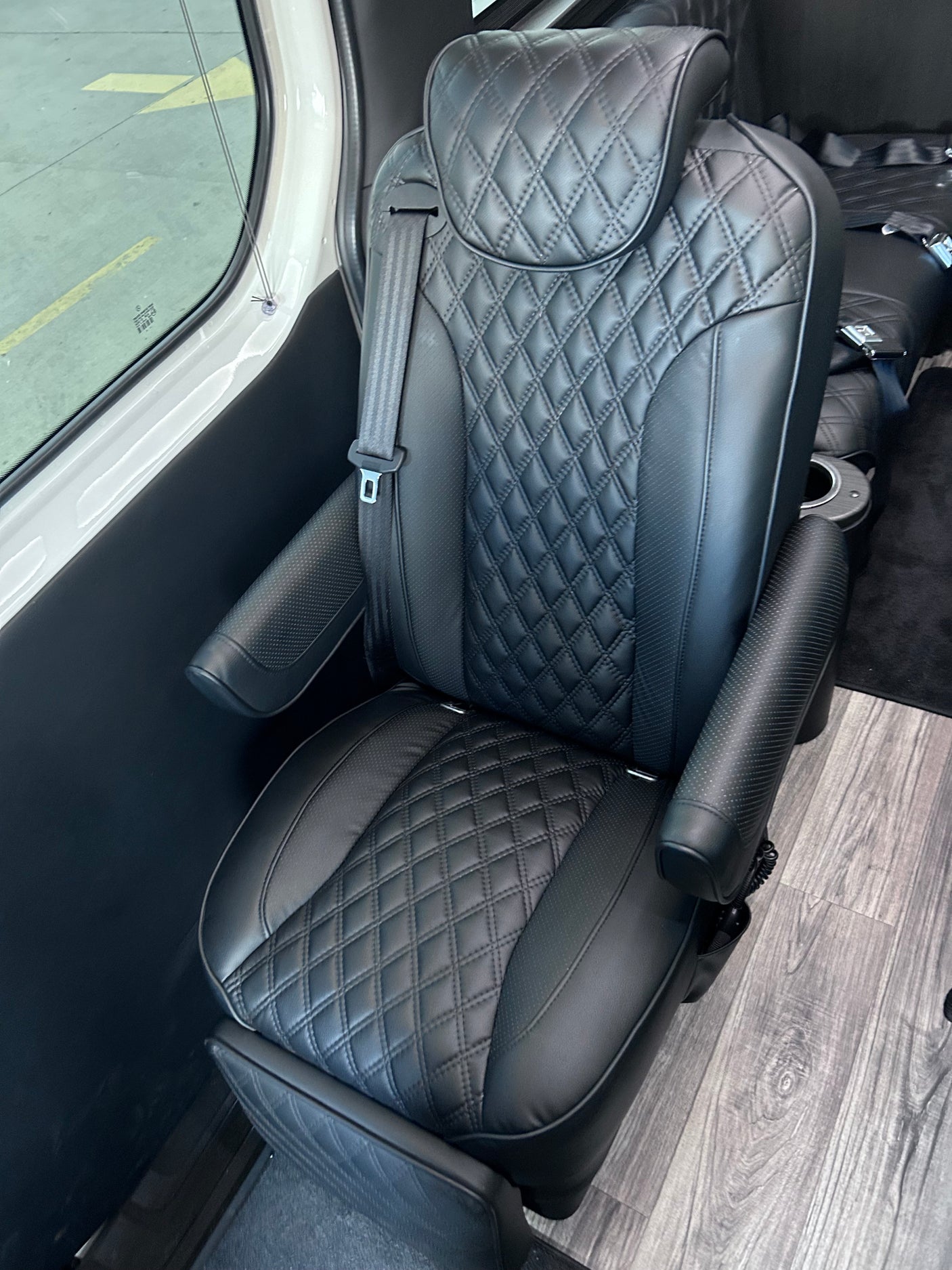 Luxury black leather captain's chair in a premium RV rental interior, featuring diamond stitching and armrests.