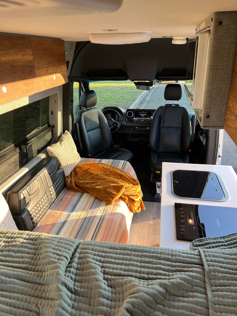 This RV rental interior features a bed, kitchen counter with cooktop, and driver's cabin, ready for adventures. — photo 6