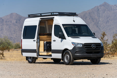 White Mercedes-Benz Sprinter camper van, an RV rental, parked in the desert mountains with its custom interior.