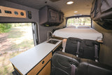 Spacious RV rental interior featuring a bed, kitchen, and seating. This camper van is ready for outdoor adventures.