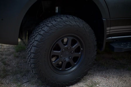 Rugged black all-terrain tire and wheel on an RV rental van, with a side step visible. Ready for adventure!