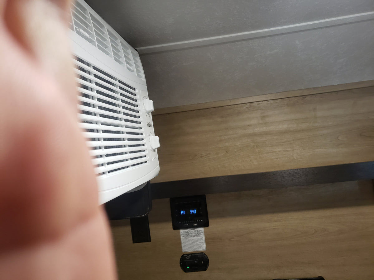 Inside an RV rental: a white Haier AC unit, digital clock (PM 9:40), and CO detector are visible against wood paneling. — photo 9