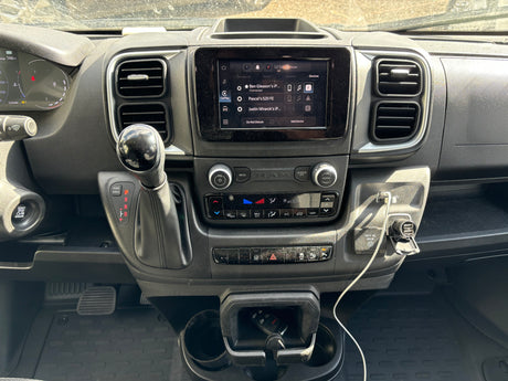 RV rental dashboard with infotainment screen, gear shifter, climate controls, and charging ports. Modern vehicle interior.