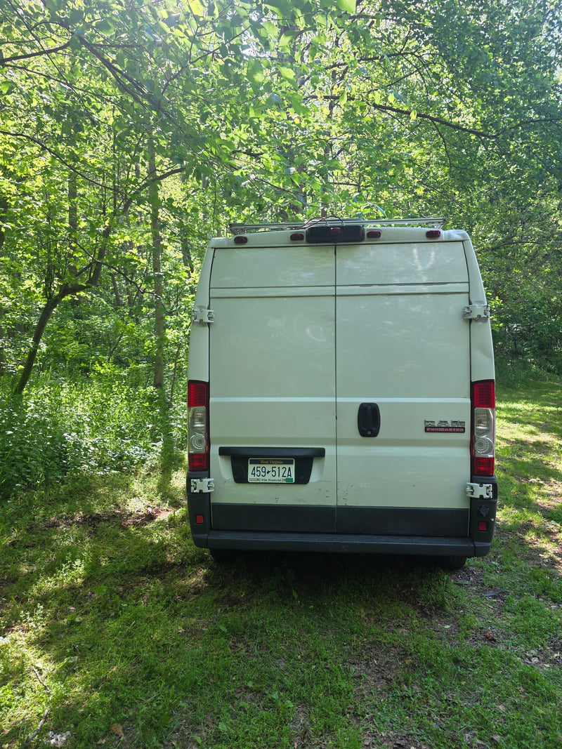 White Ram ProMaster van (rv rental) parked in a sun-dappled forest, showing its rear with a West Virginia license plate. — photo 12