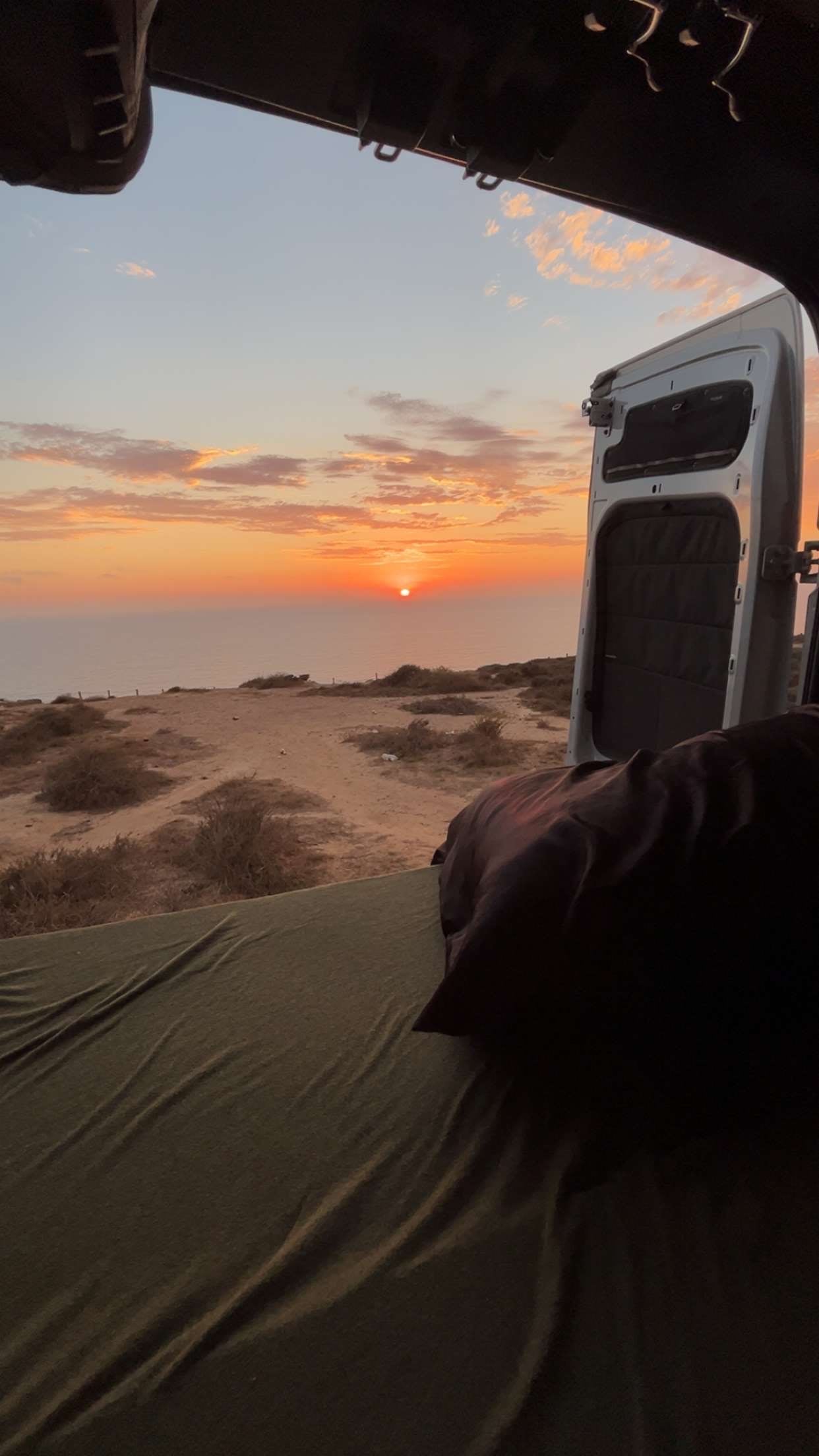 Breathtaking RV rental sunset ocean view from inside the van. Perfect for tranquil van life camping adventures.