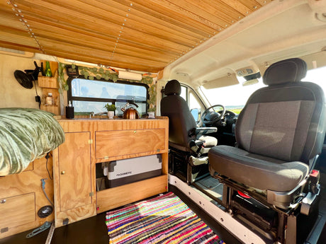 Cozy RV rental interior with wood-paneled ceiling, custom kitchen, bed, and Dometic cooler for your next adventure.