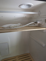 rv rental compact wet bath interior, showing shower controls, hose, white towel, and slatted wooden shelf.