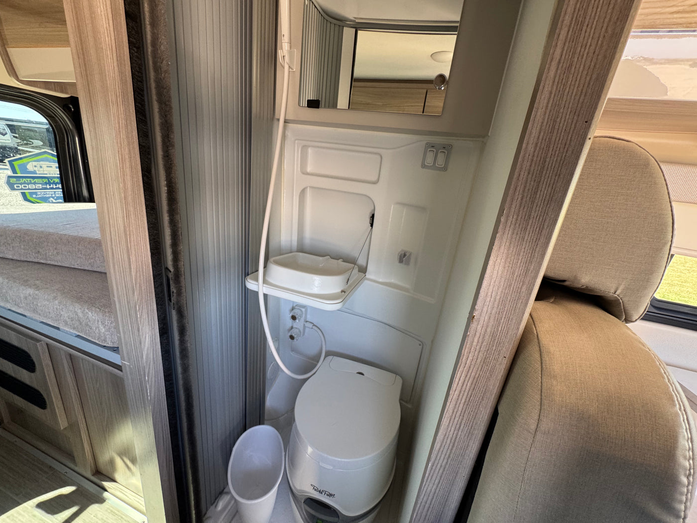 Compact RV rental wet bath featuring a toilet, fold-down sink, and shower. Bunk beds are visible on the left. — photo 6