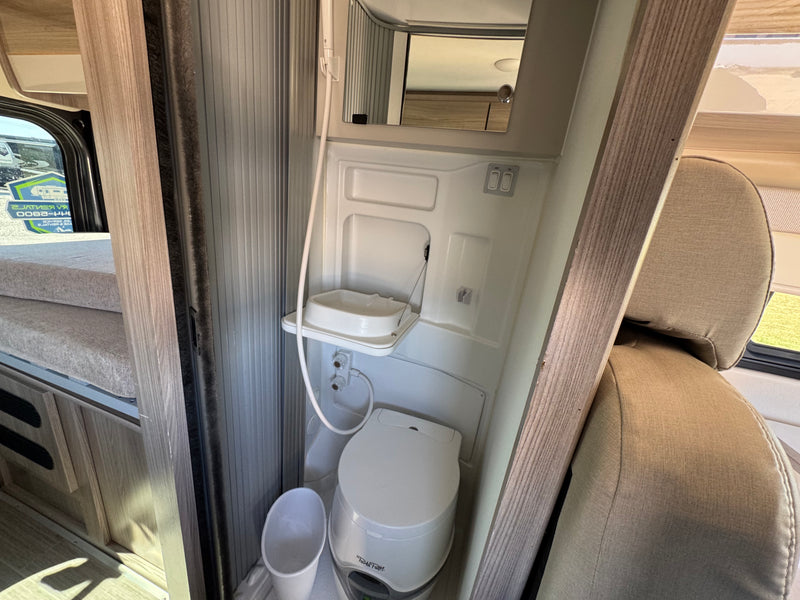 Compact RV rental wet bath featuring a toilet, fold-down sink, and shower. Bunk beds are visible on the left. — photo 6
