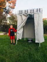 Young boy by a portable privacy tent with a toilet, ideal for your RV rental camping adventure.